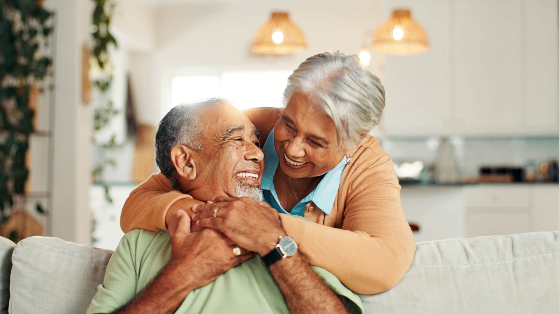 couple smiling hugging on a couch