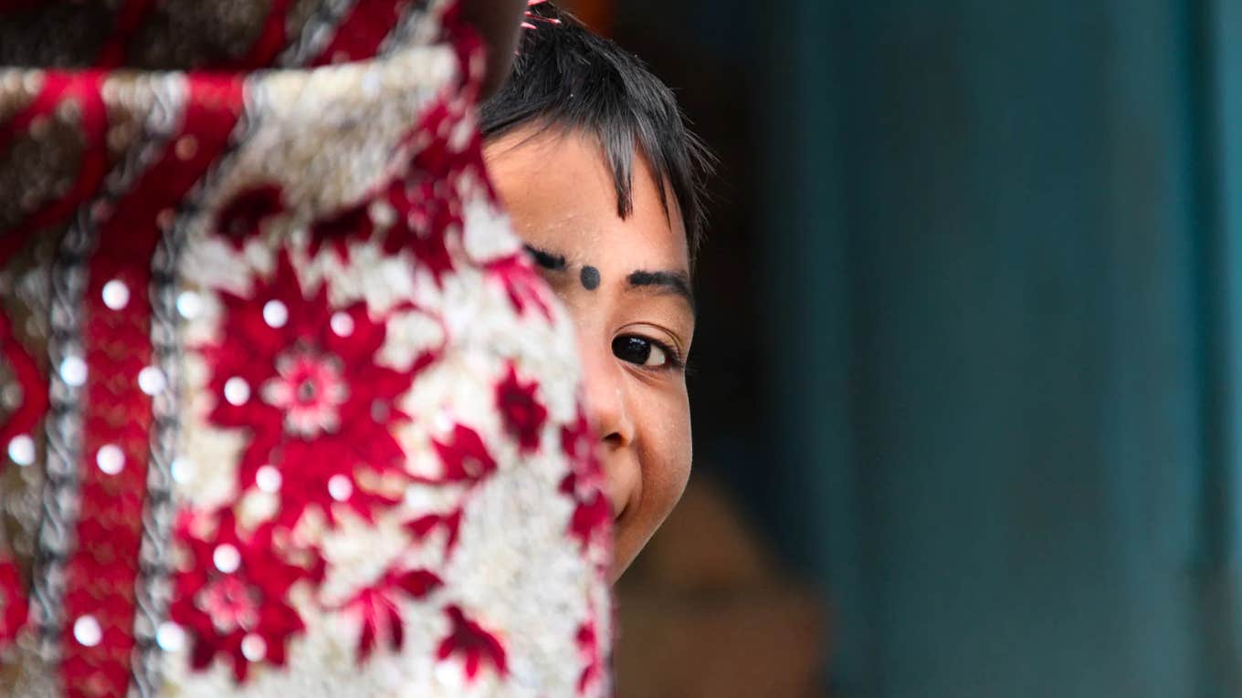 Young Pakistani girl holding her mother’s waist, reflecting the deep bond and pain of being a daughter of a sold mother.