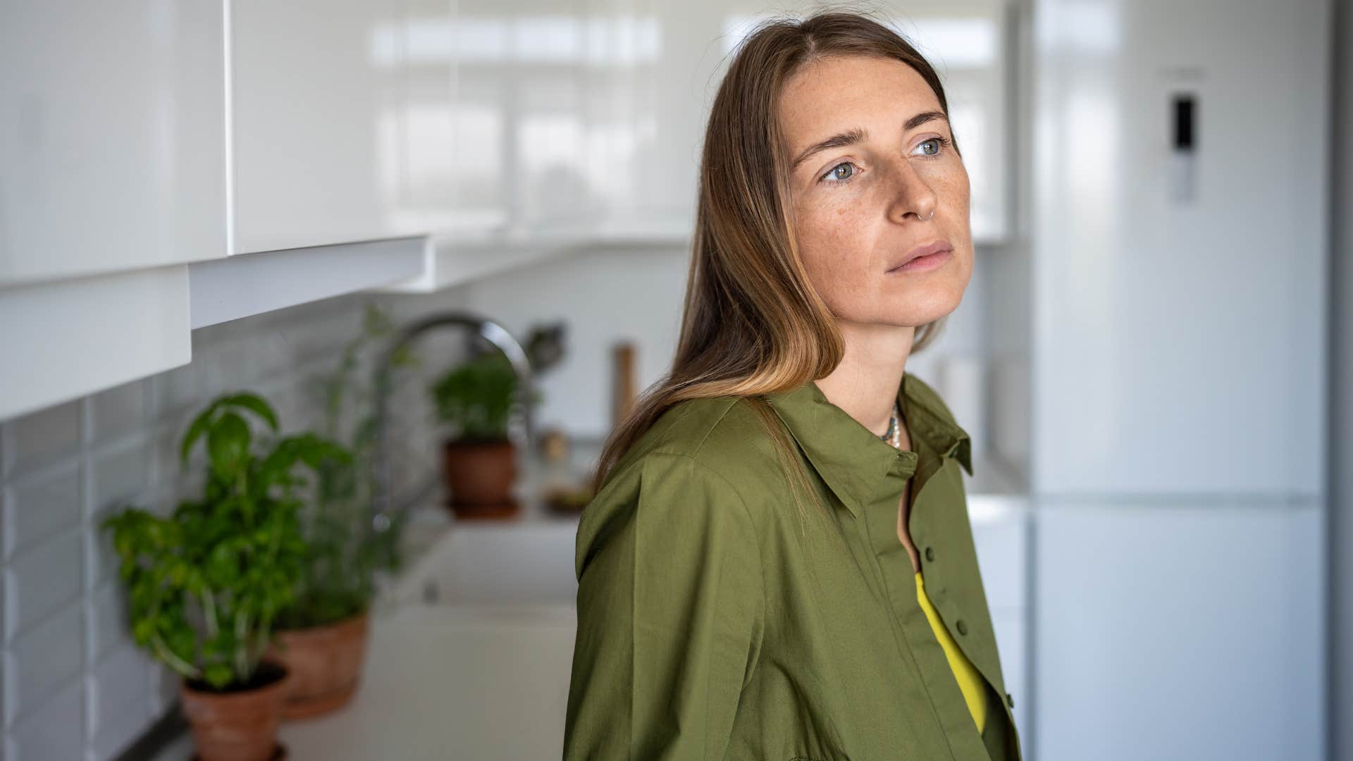 woman in green shirt stops taking photos as she looks out the window