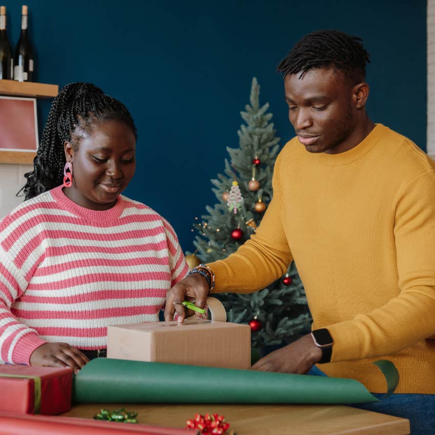 Couple wrapping gifts after only spending 1% of their income on holiday shopping