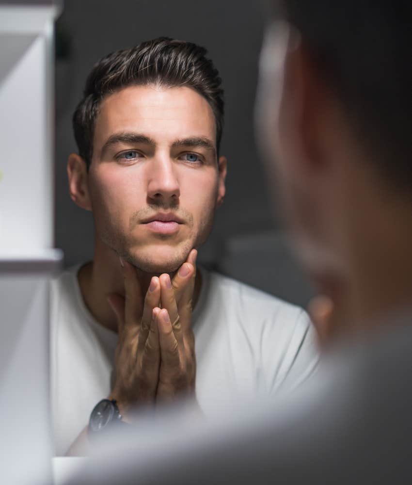 man looking at eyebrows in mirror