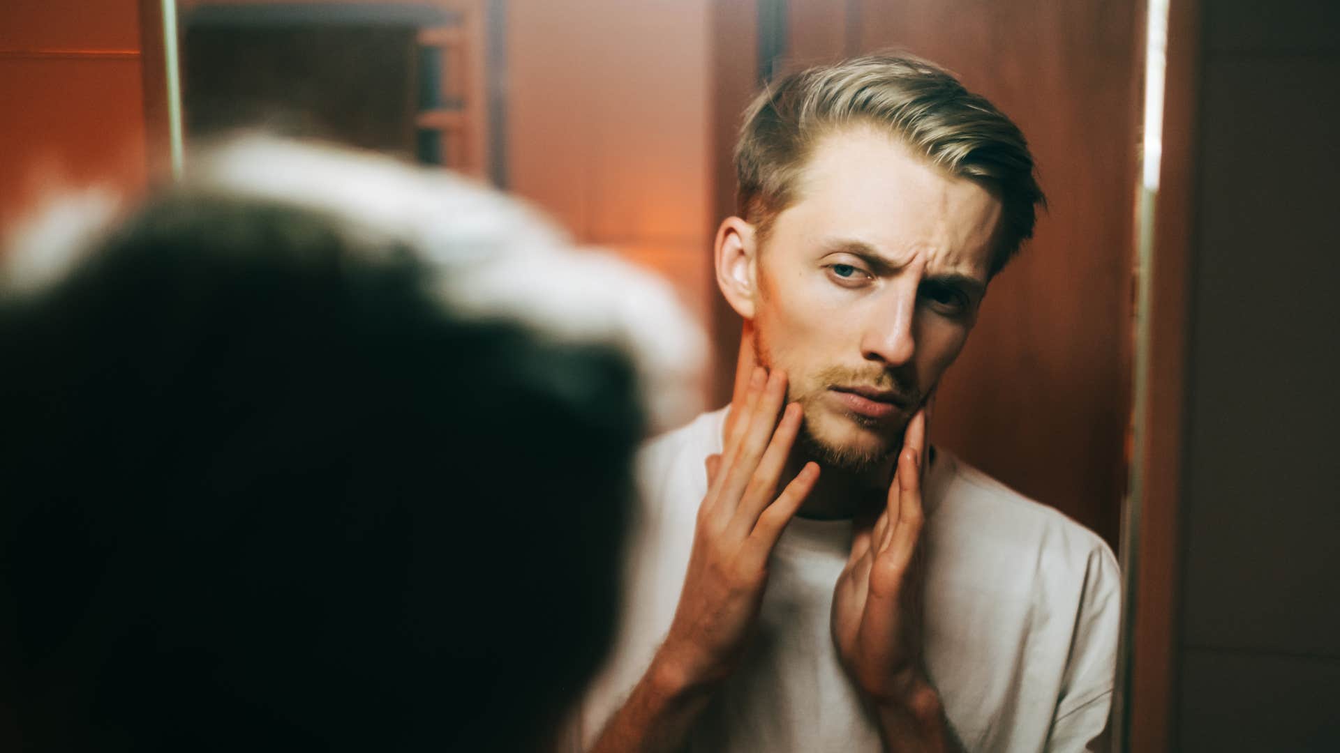 man prioritizing his appearance looking in mirror