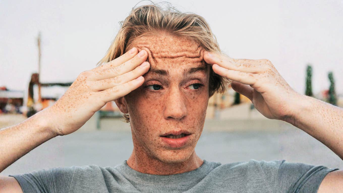 Anxious man holding his temples with wide eyes, when anxiety causes racing heart and stress.