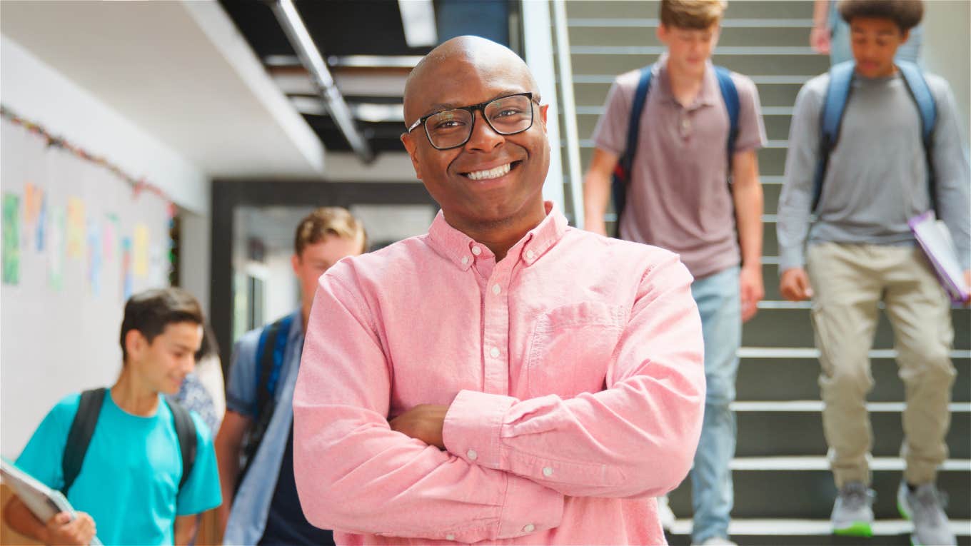 high school teacher smiling while standing in hallway at school