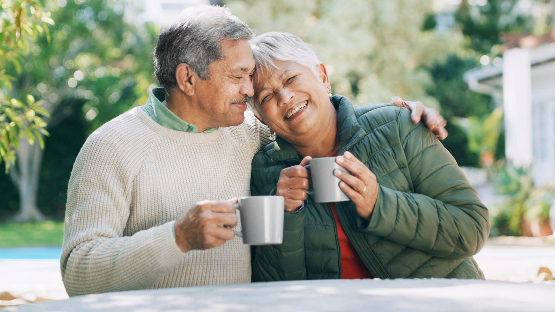 couple smiling and hugging while drinking coffee together