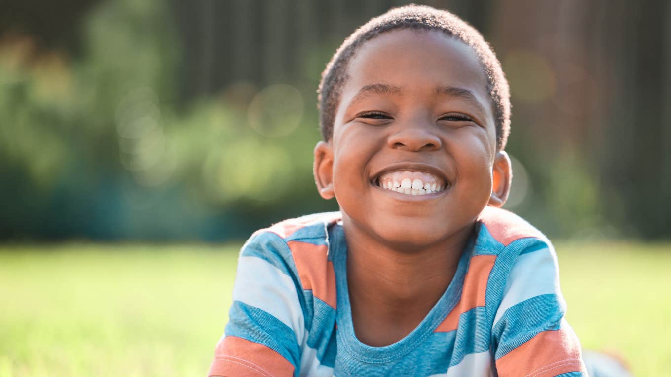 little boy smiling while lying on grass outside