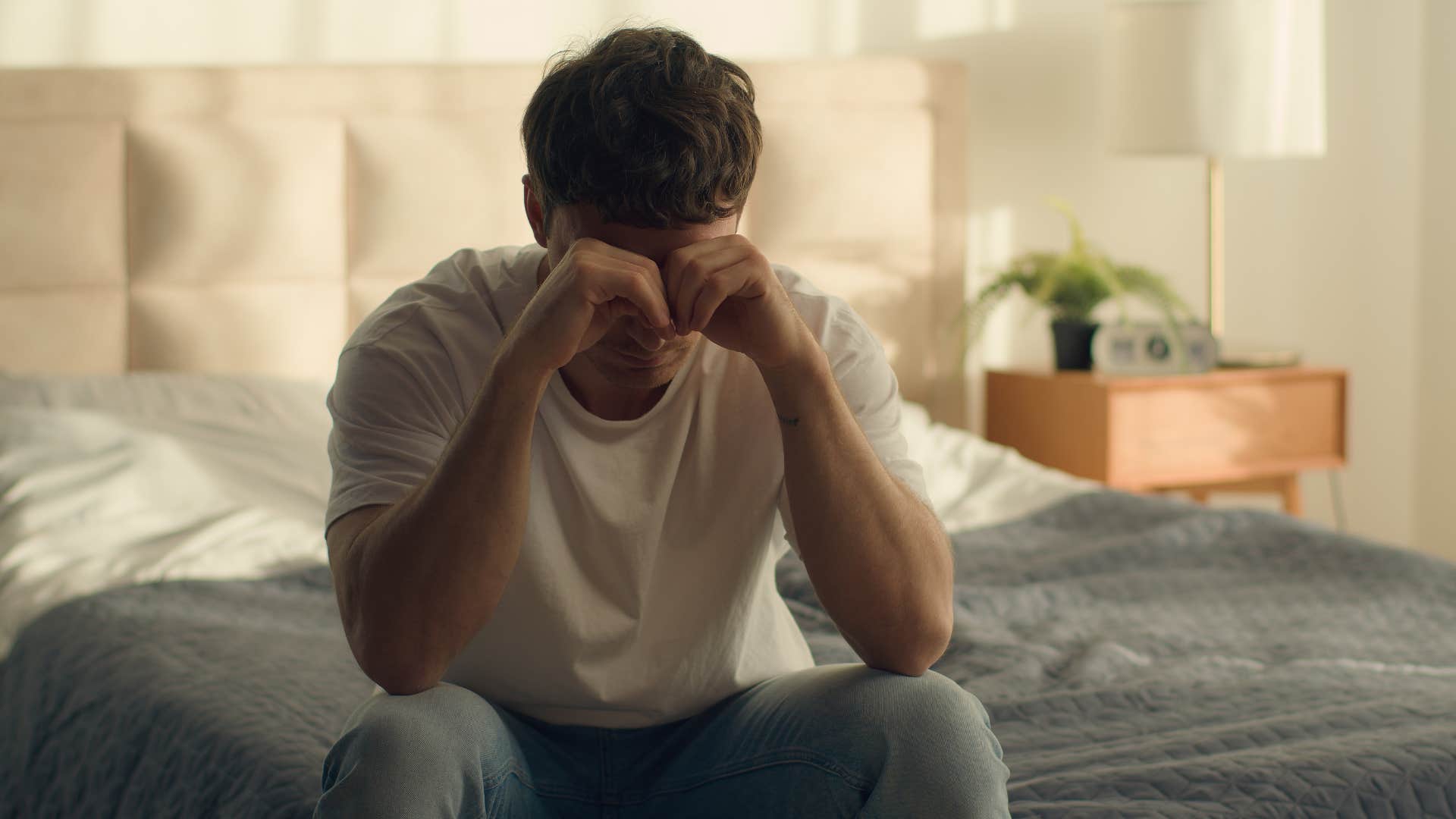 lonely man sitting in bed thinking upset