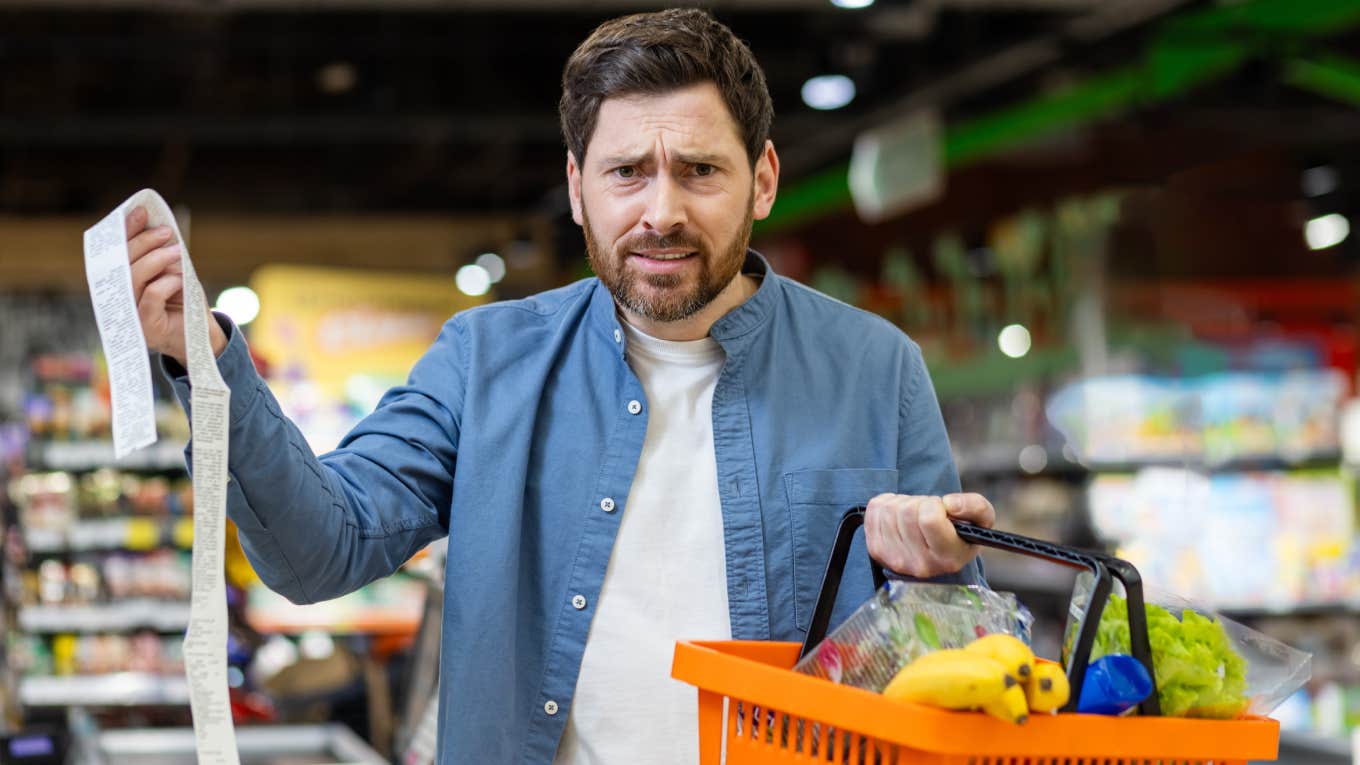 frustrated man holding receipt after grocery shopping