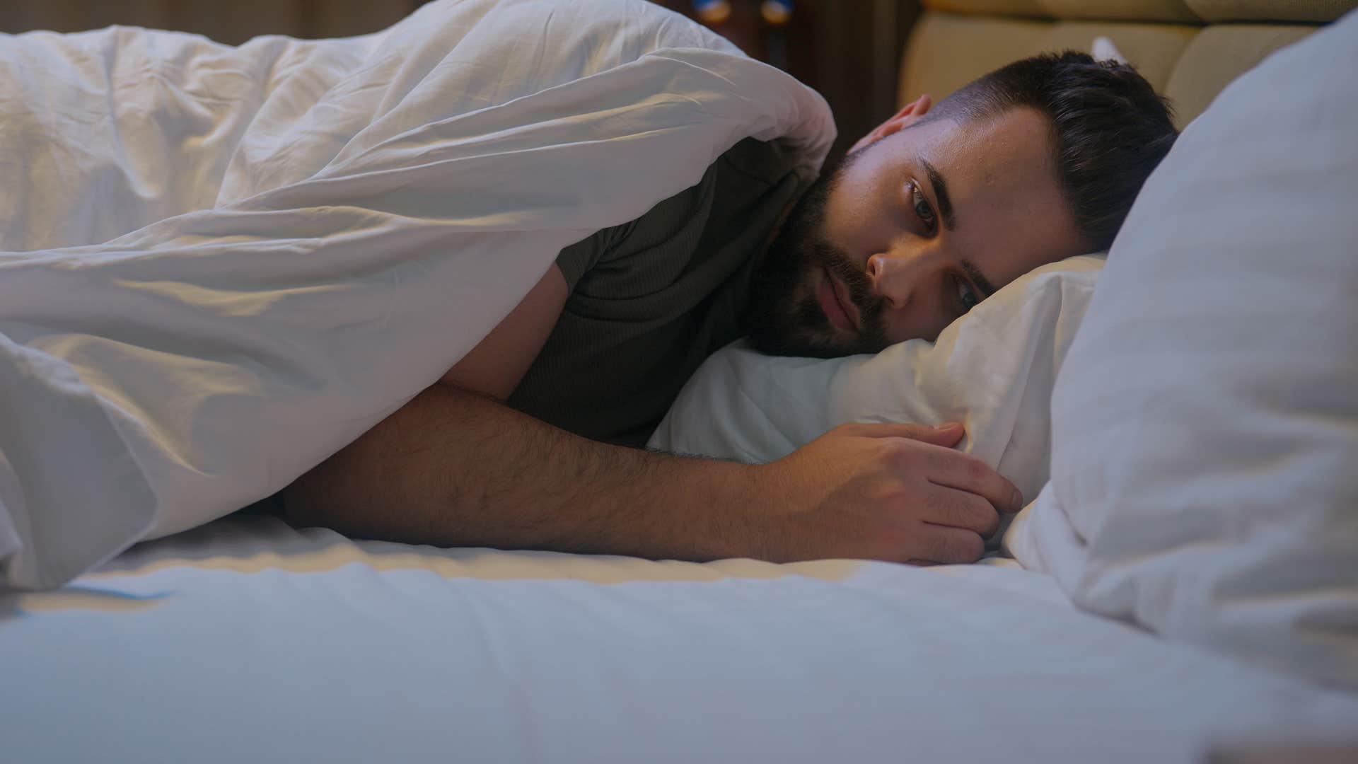 upset man lying awake in bed