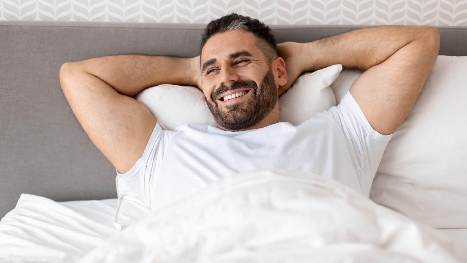 happy man sitting back in bed feeling pride