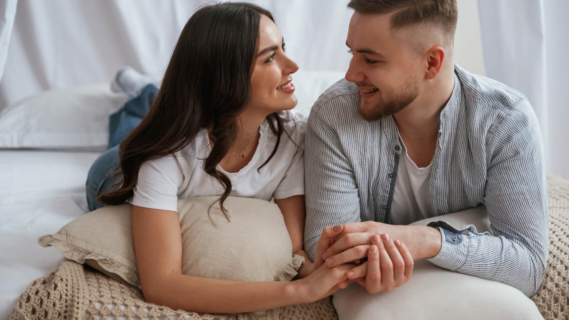 couple having conversation while lying on bed