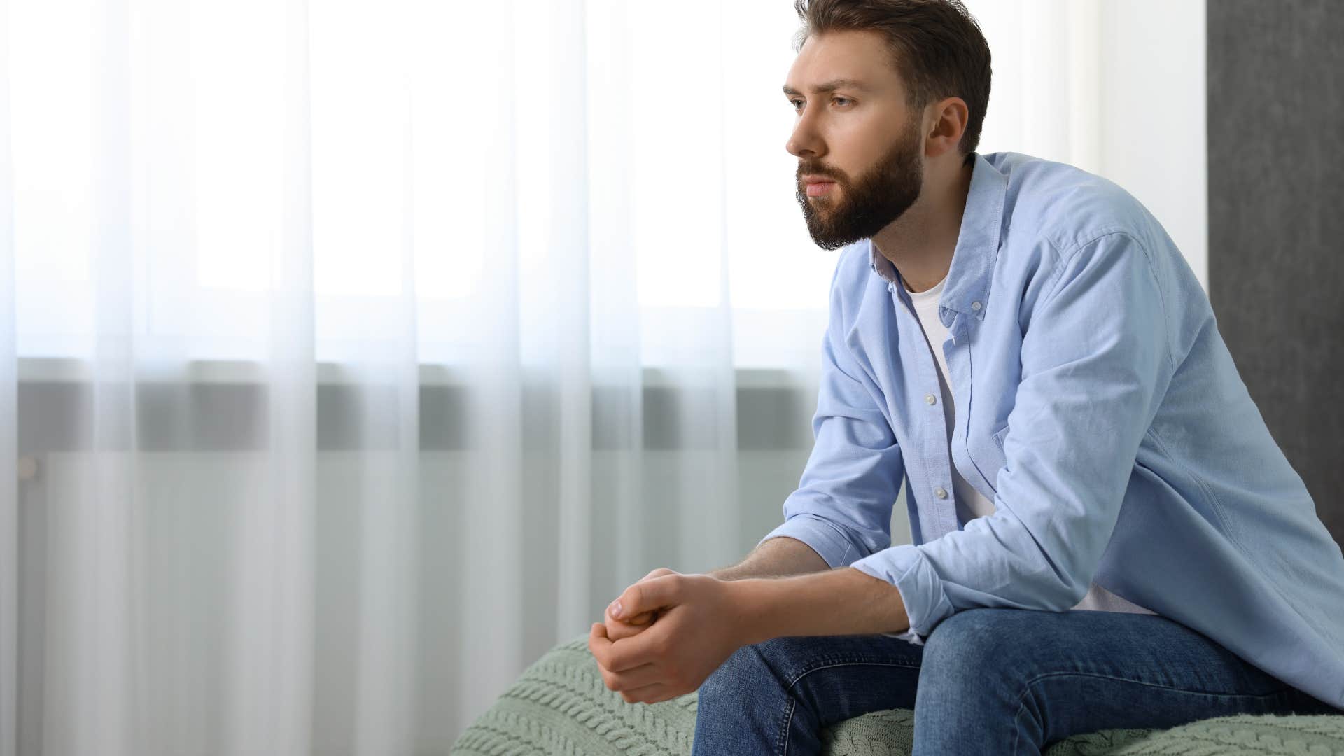 upset man sitting on edge of bed wishing for spontaneity in marriage