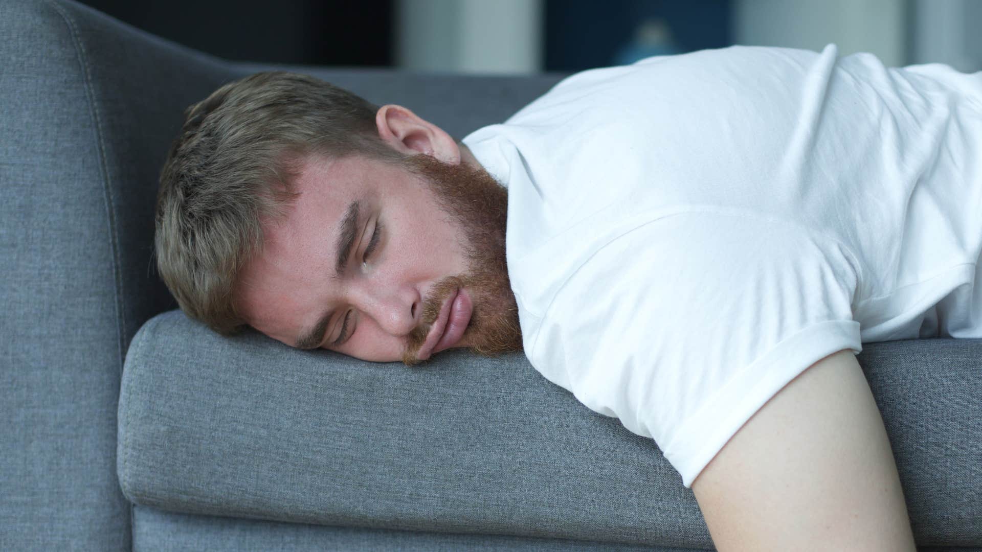 man who feels unloved sleeping on the couch alone