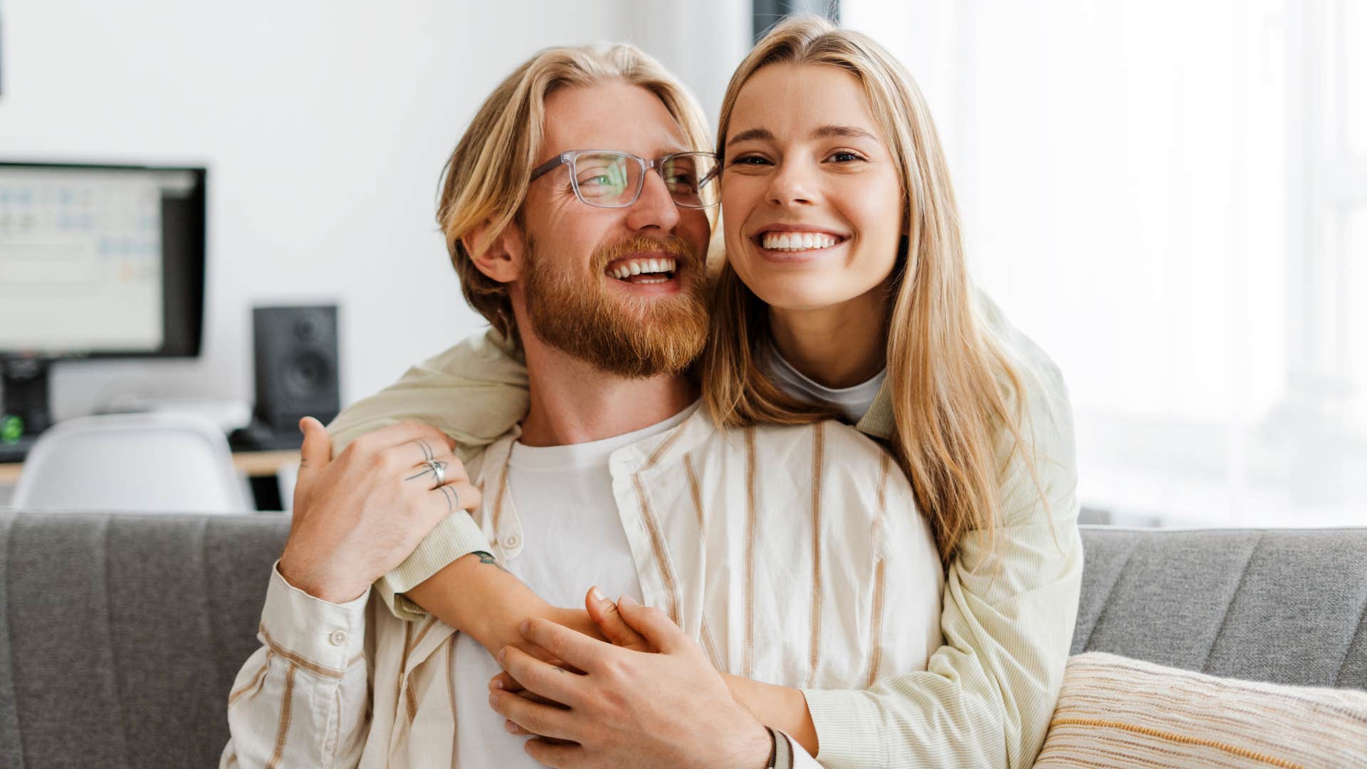 woman hugging husband sitting on couch