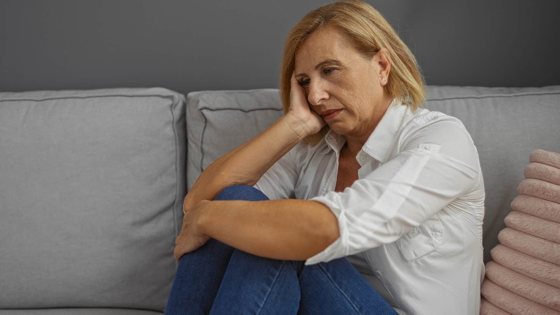 Woman who's grieving sitting on the couch.