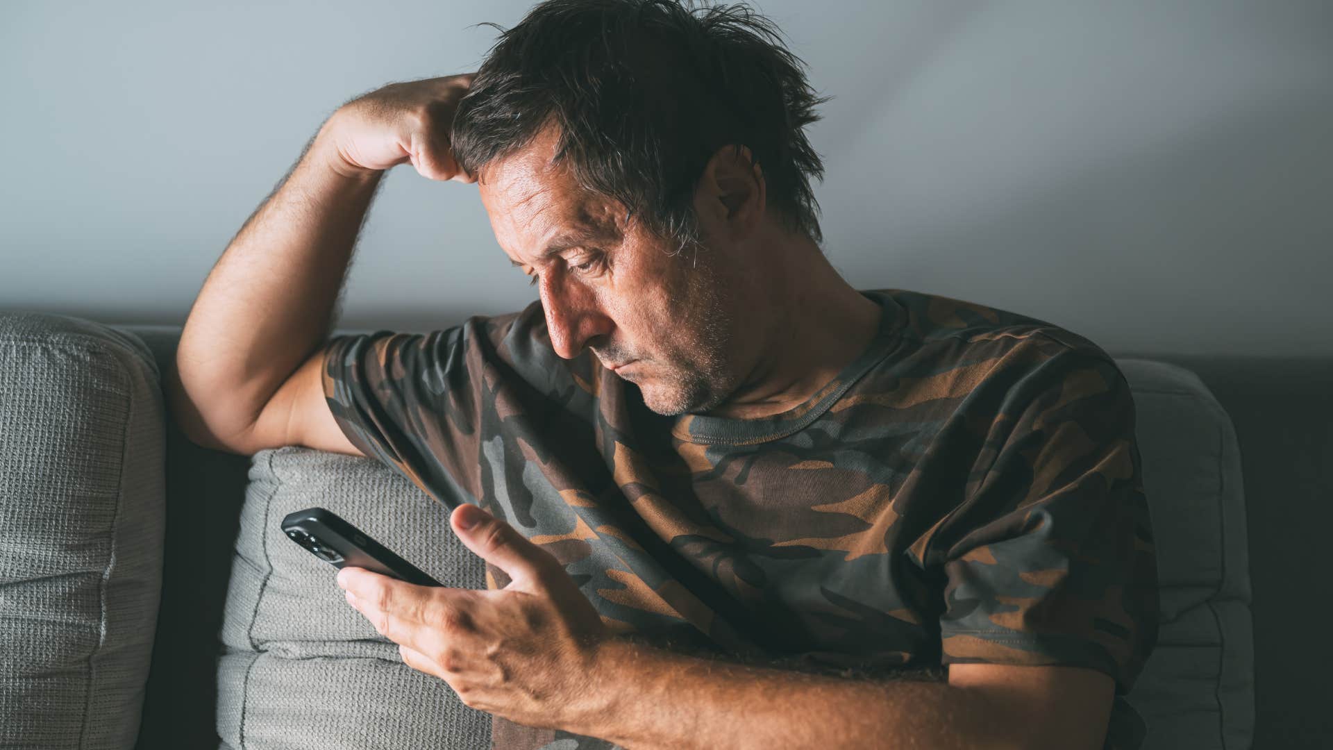 Man who's lost confidence in his appearance looking at his phone.