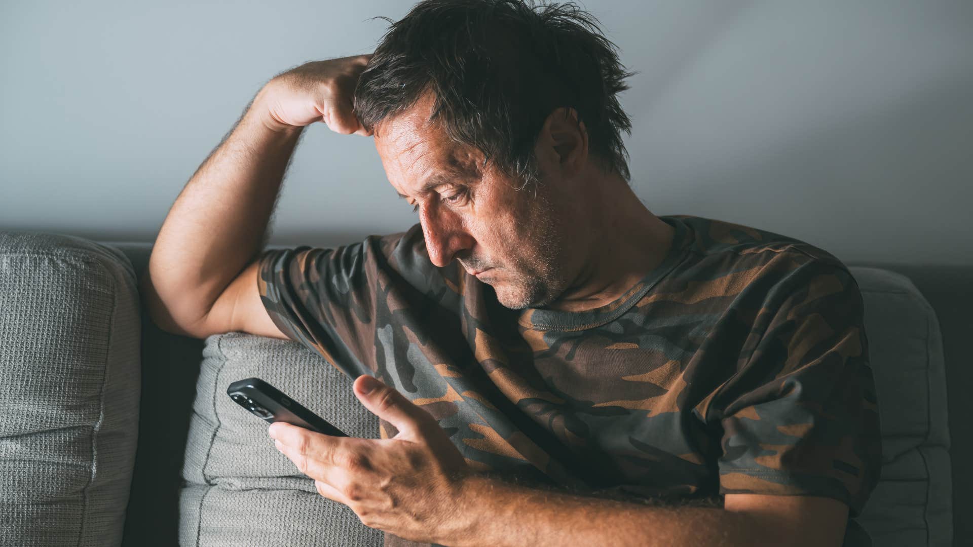 upset man looking at his phone while grieving