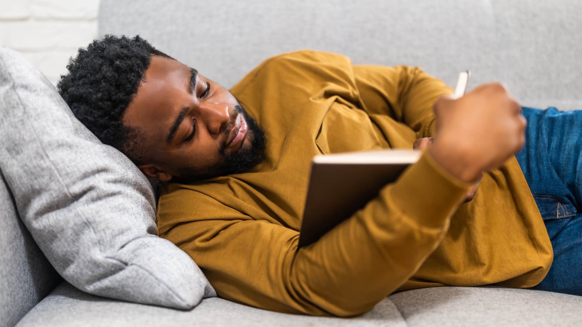 man reading a book in bed after setting boundaries with his phone
