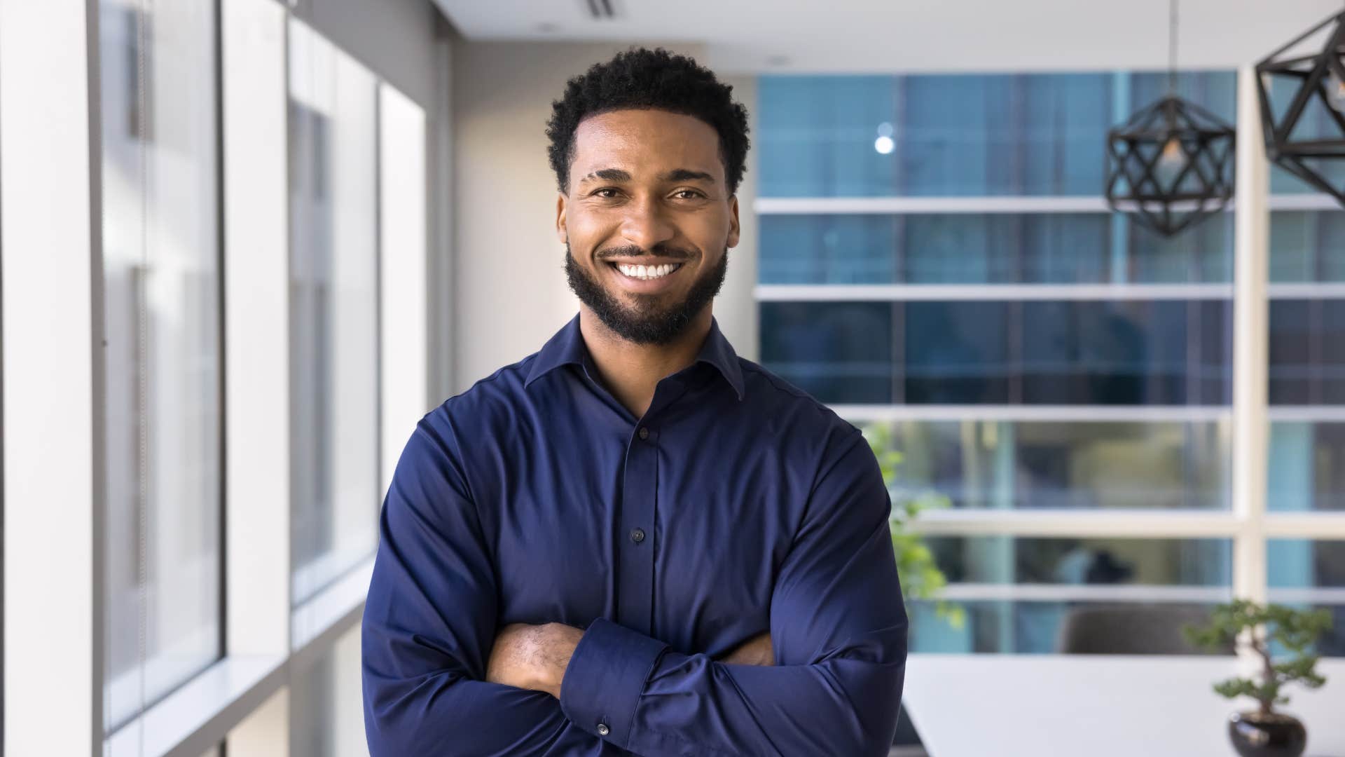 businessman standing in office with arms crossed