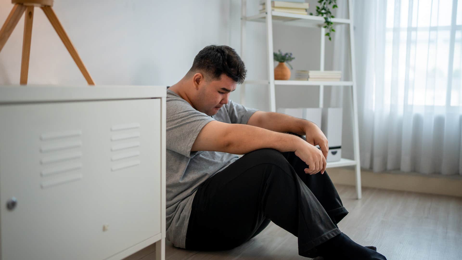 upset man sitting on floor of his room