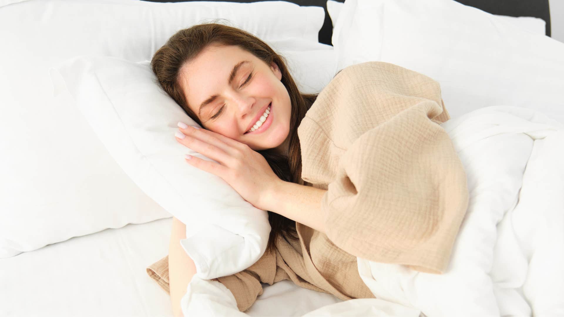 affectionate woman smiling in bed hugging her pillow