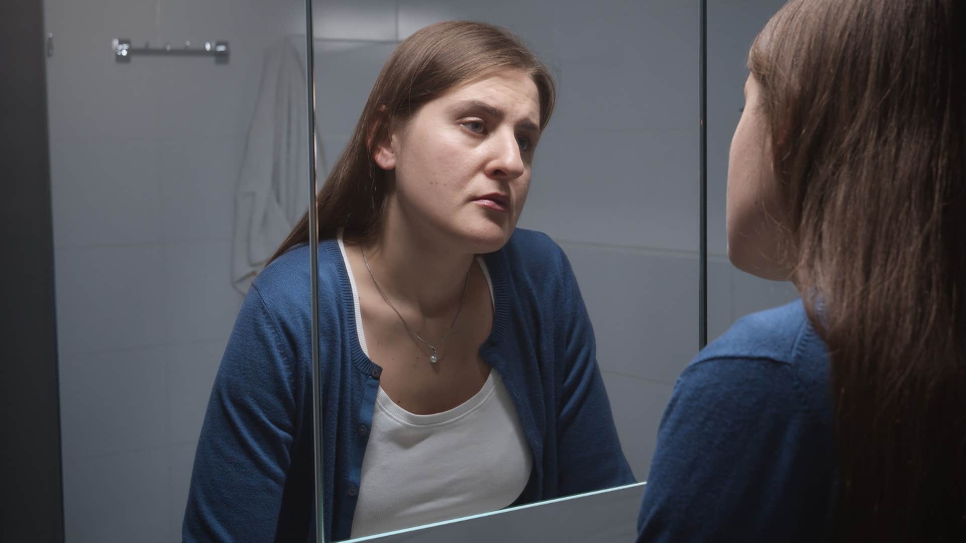 Upset woman in a bathroom with the same reused towels. 