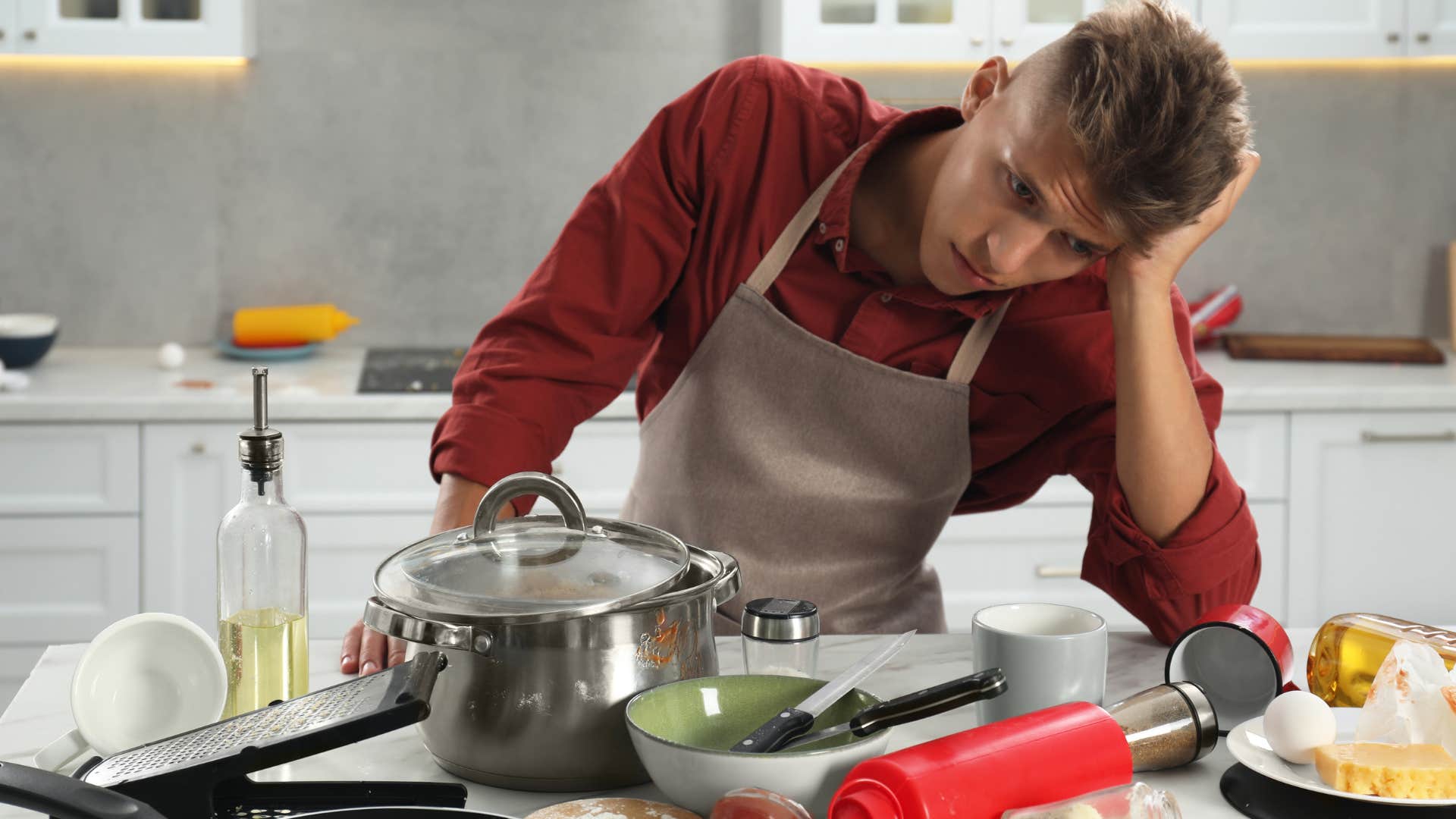 Man looking at dirty dishes soaking in the sink.
