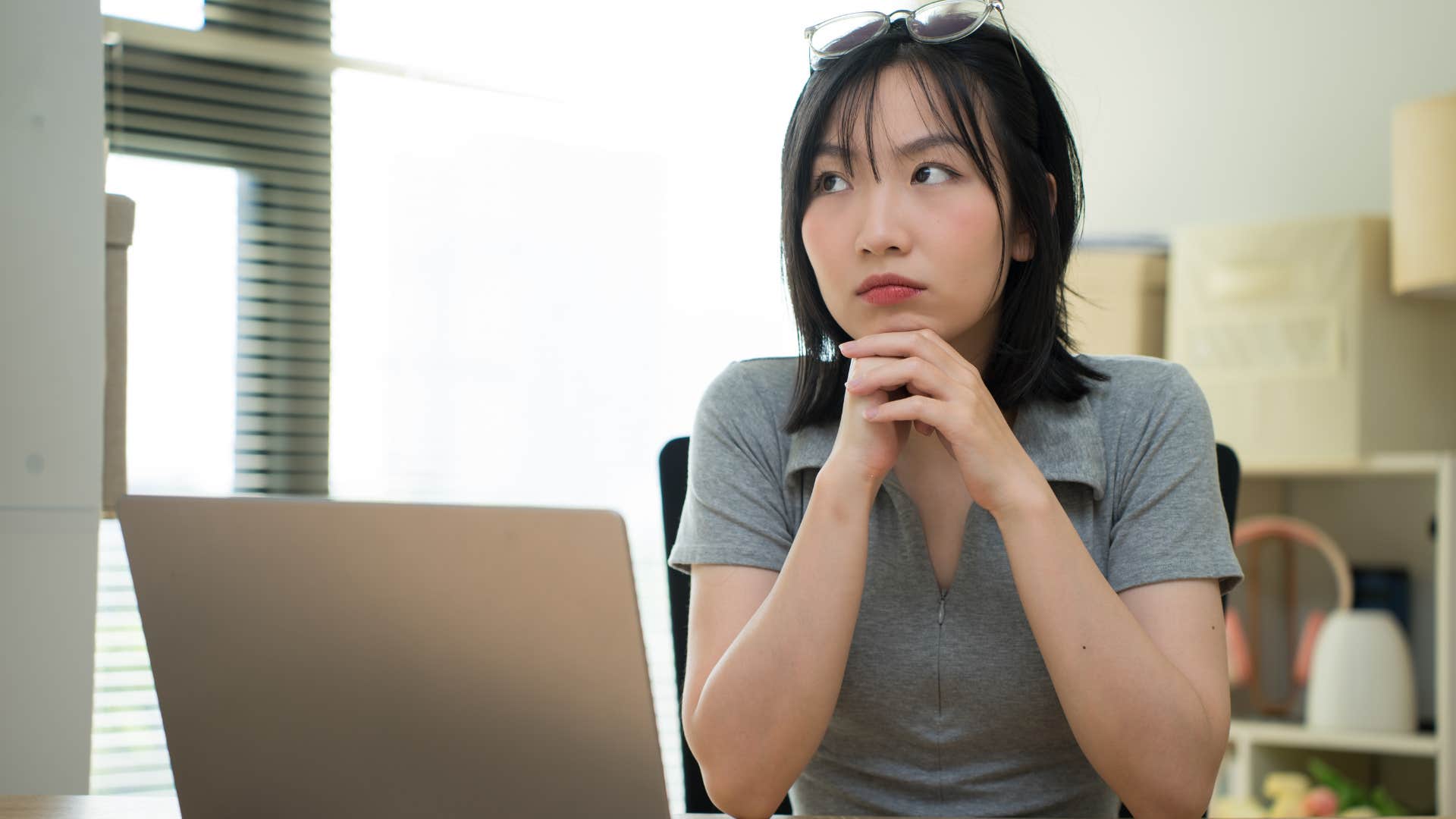 Woman looking at a journal buried under clutter at home.