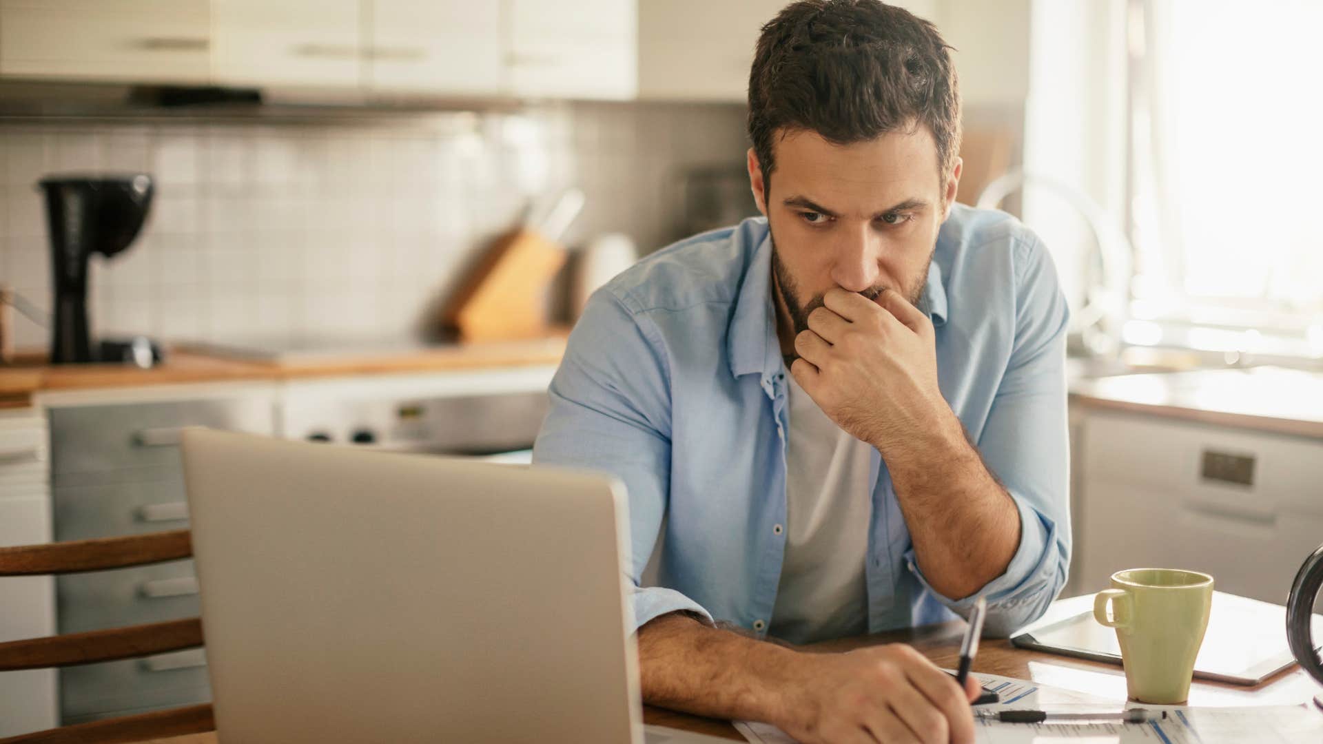 Man working with a million empty coffee mugs at home.