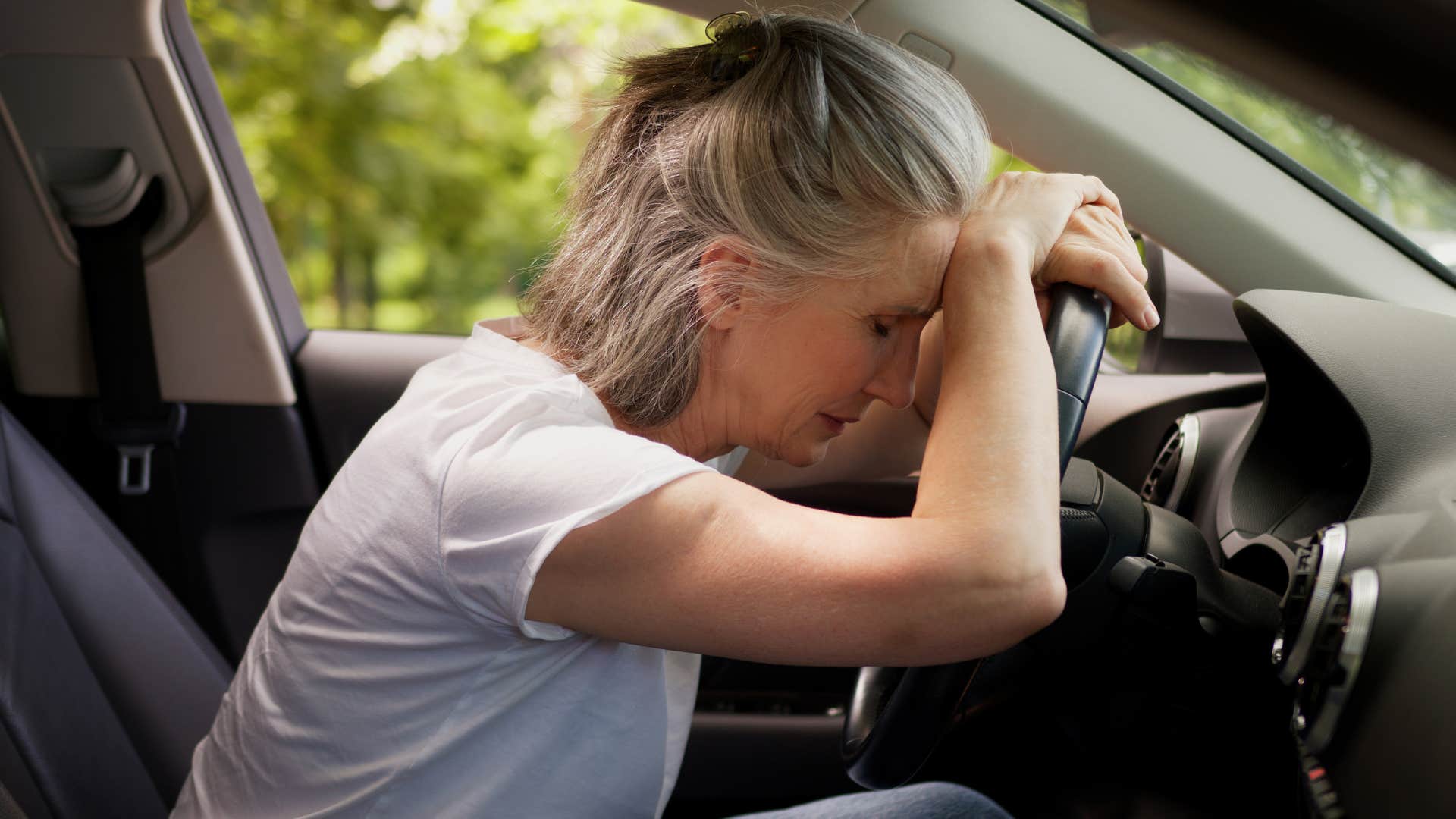 sweating woman sitting in a car with broken AC
