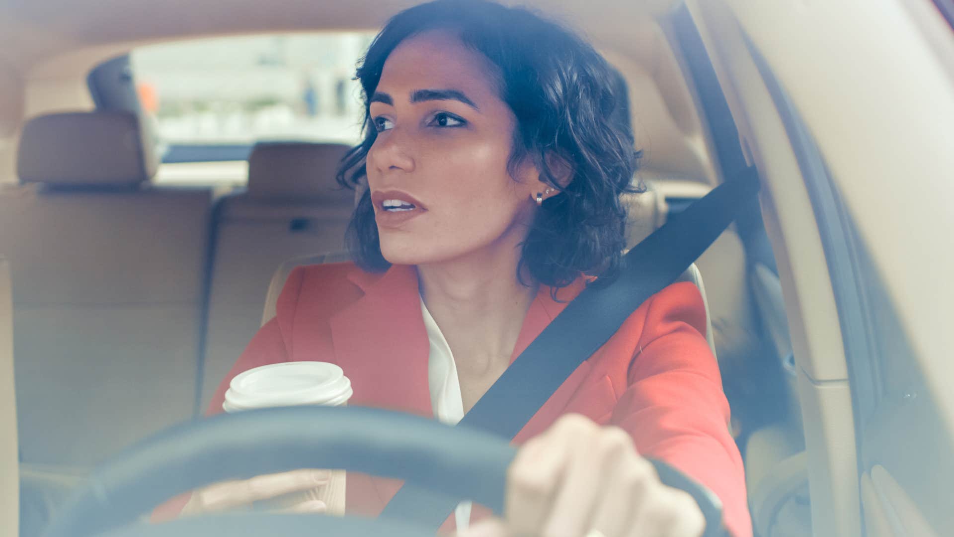 woman driving with empty coffee cups in her car