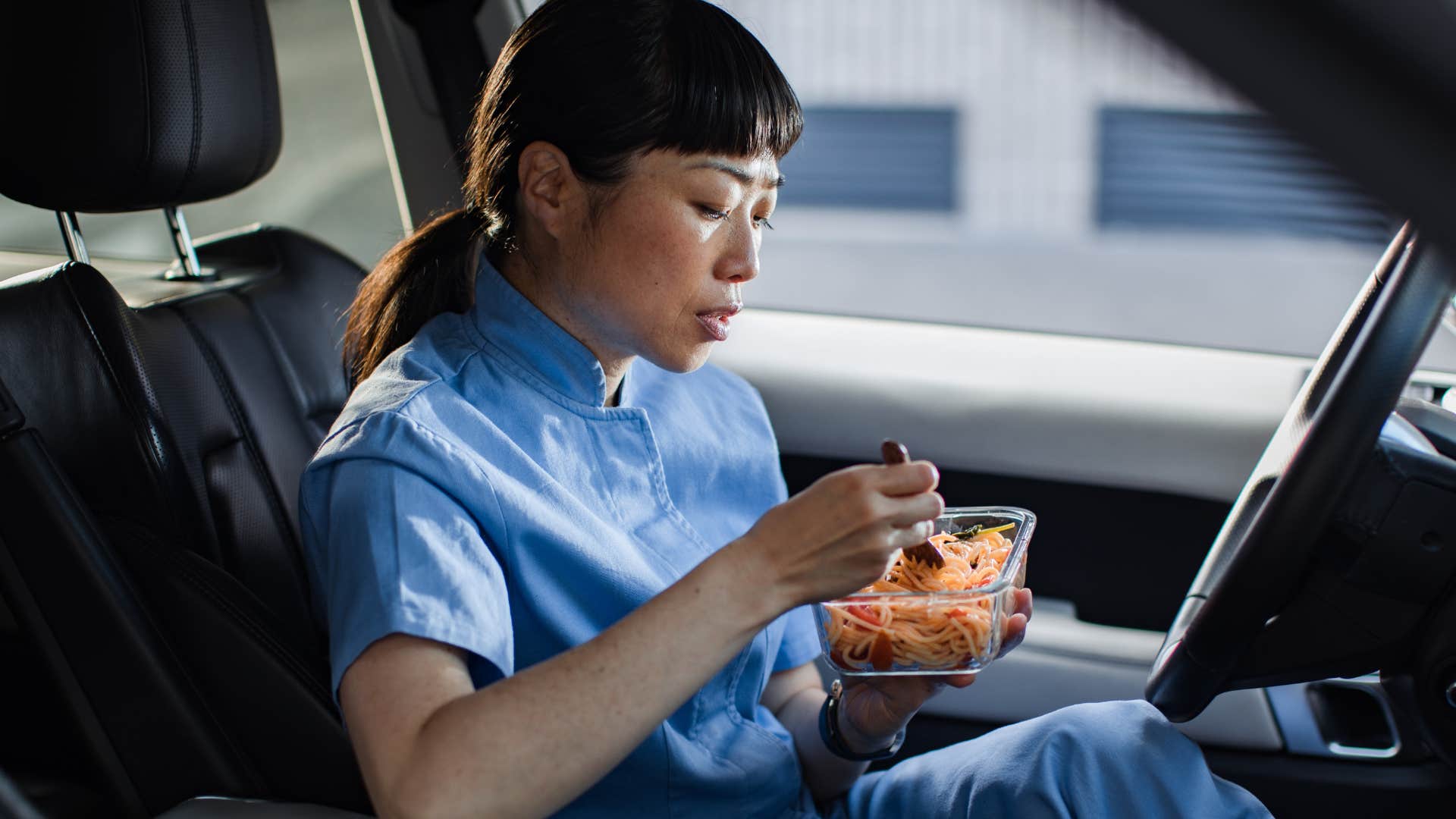 woman sitting in a car eating takeout