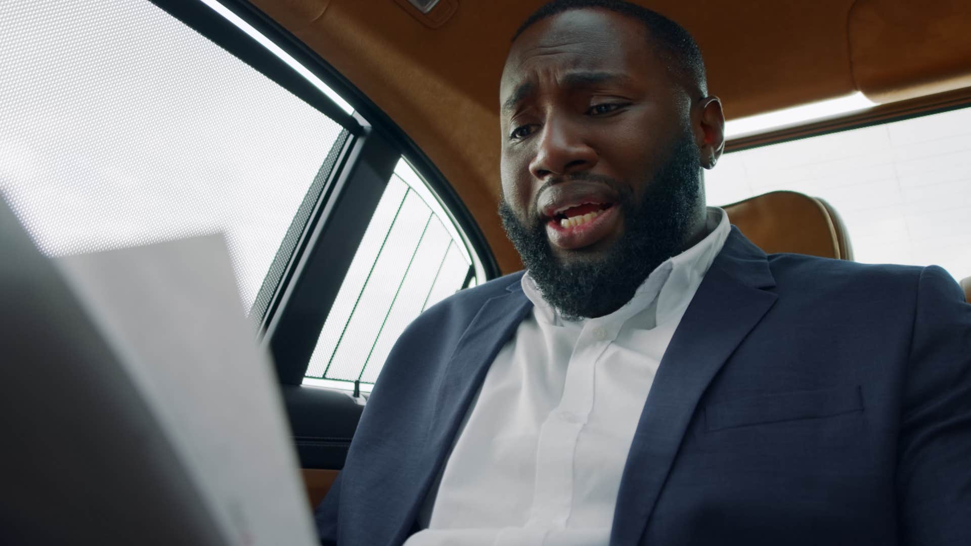 man looking at unopened mail and bills in his car