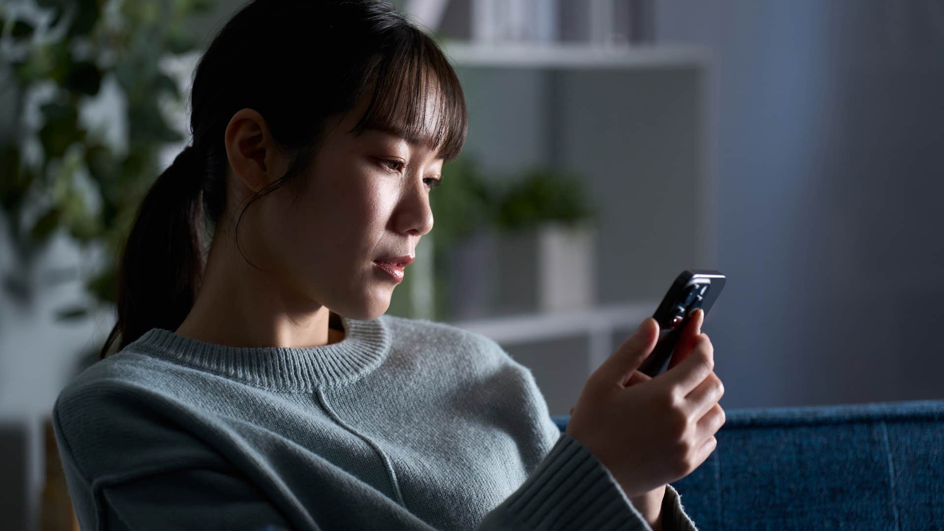 Woman sitting in her living room with burnt-out light bulbs.