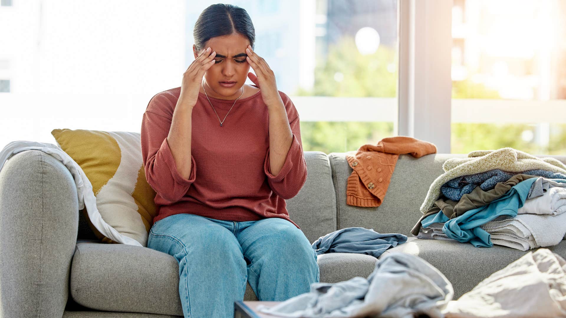 Woman sitting in her living room with clutter everywhere.