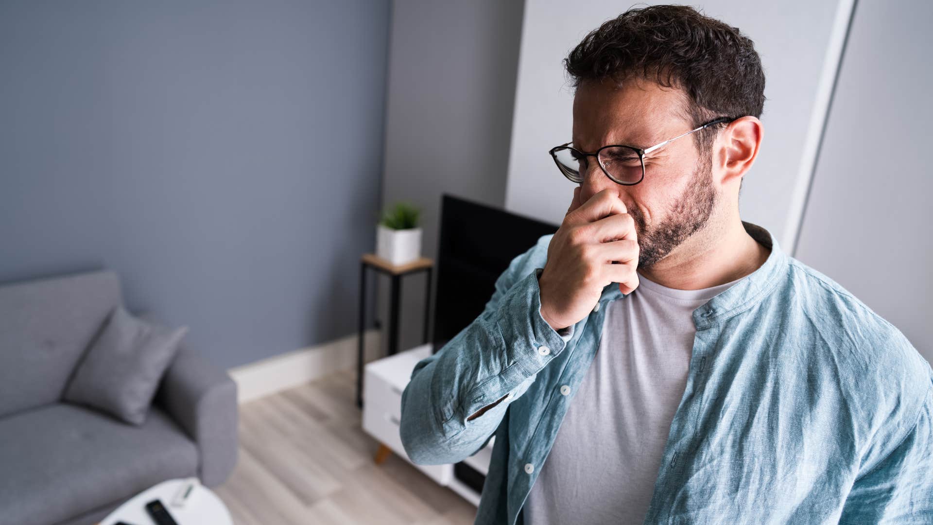 Man plugging his nose over a lingering smell at home.