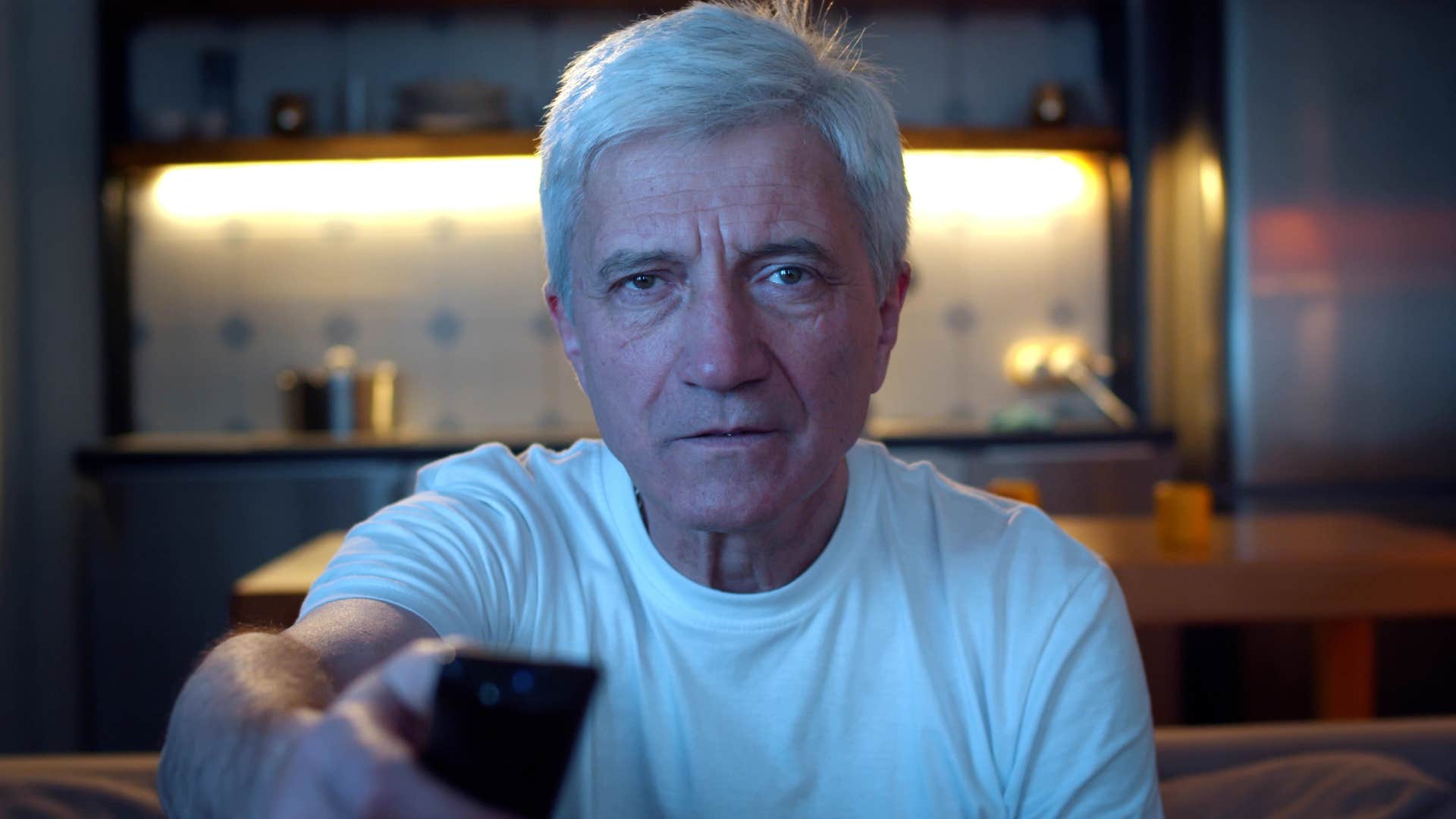 Man sitting at home with a TV that's always on.