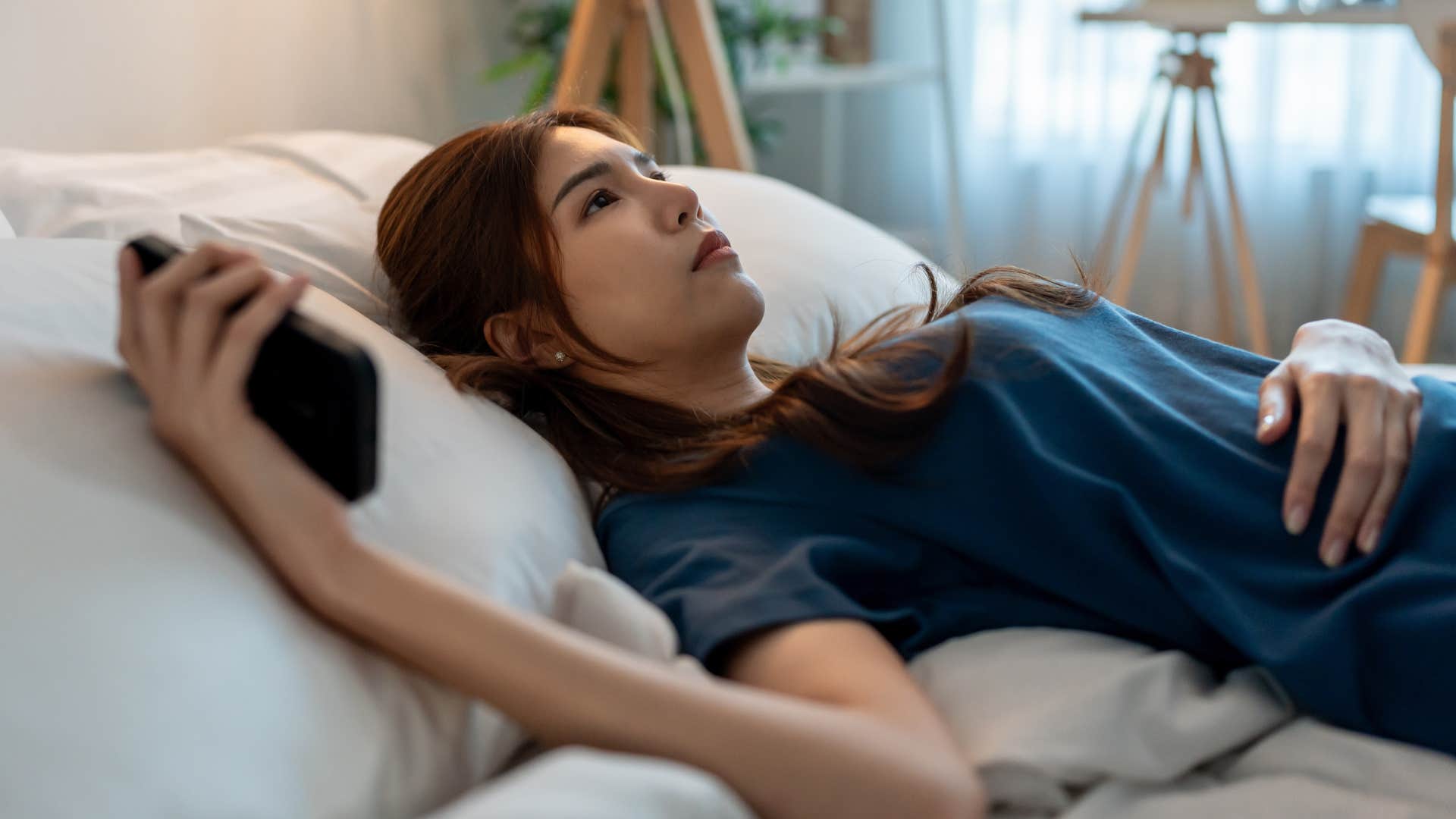 stressed woman laying in bed thinking