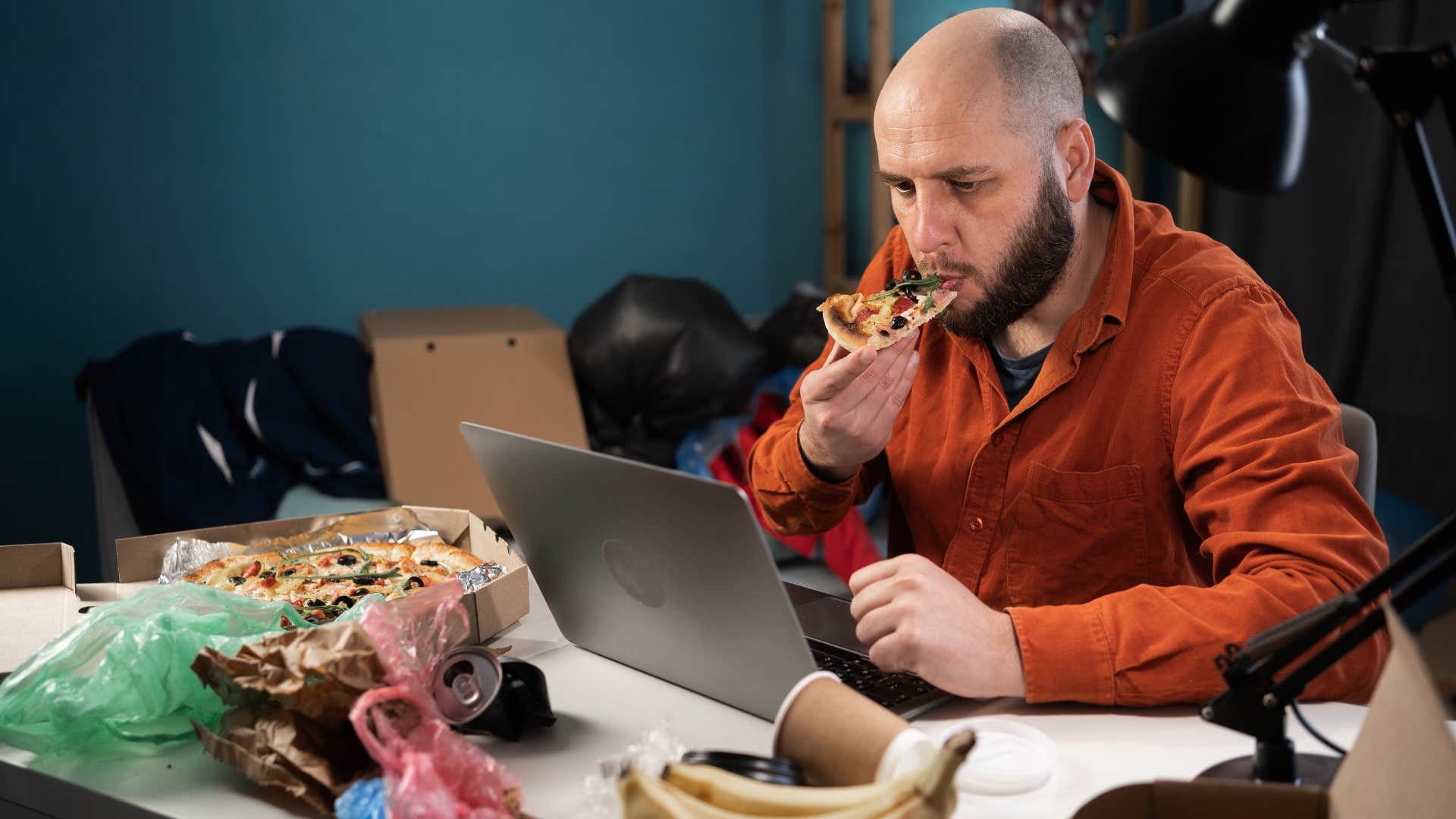 stressed man sitting at home with dirty dishes and trash everywhere