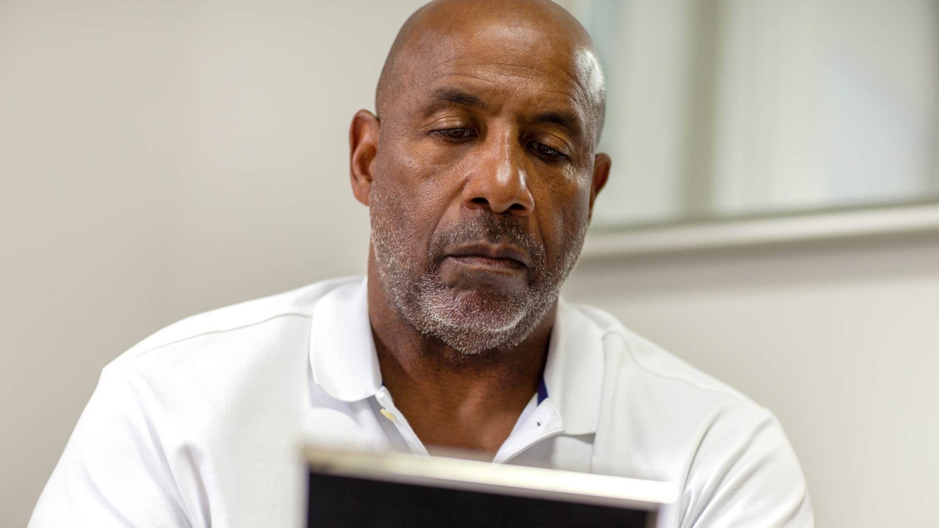 older man sitting at home looking at family photos