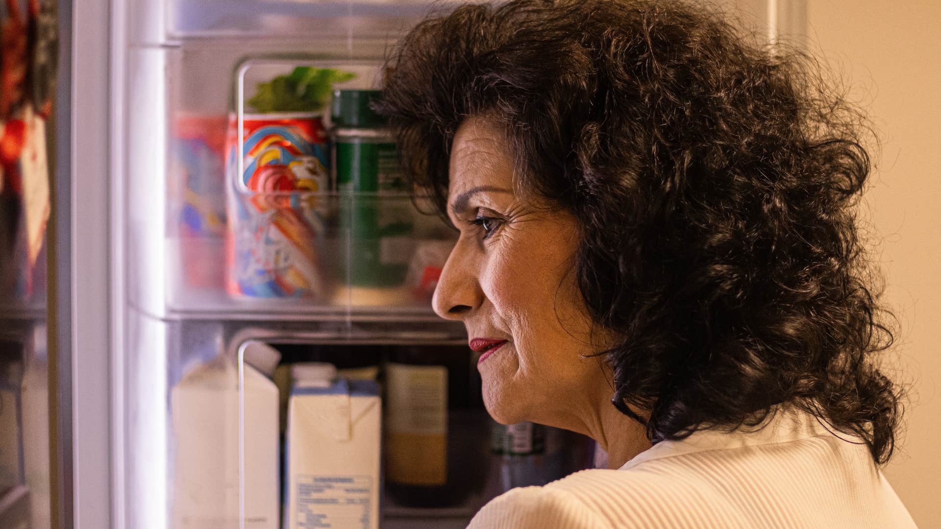 older woman looking in bare fridge