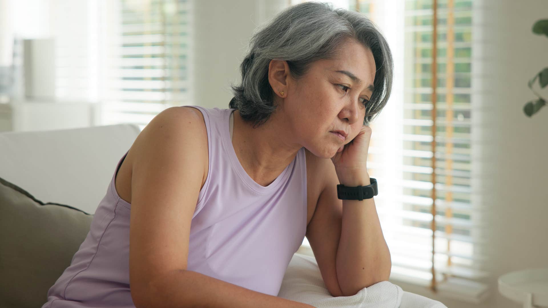 older woman looking sad sitting at home