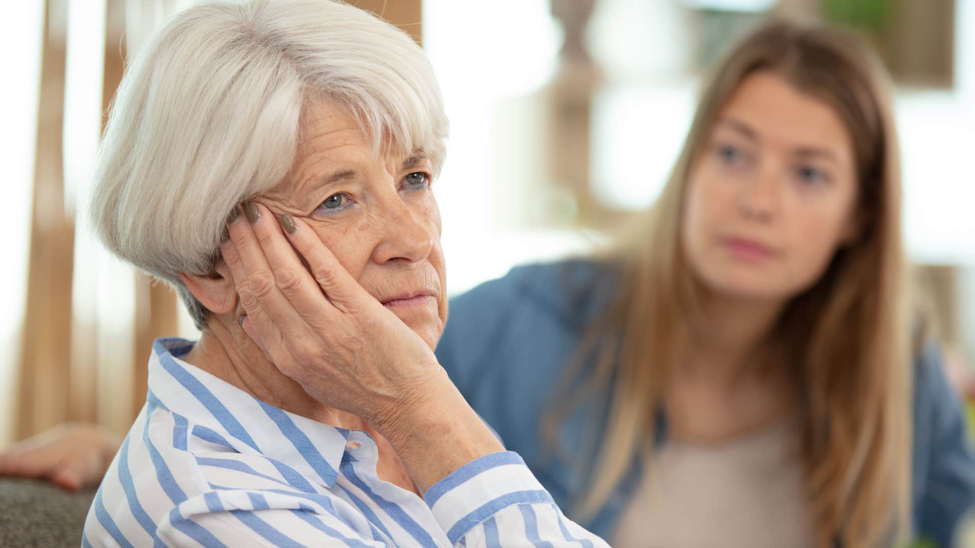 lonely older woman telling adult daughter she's fine