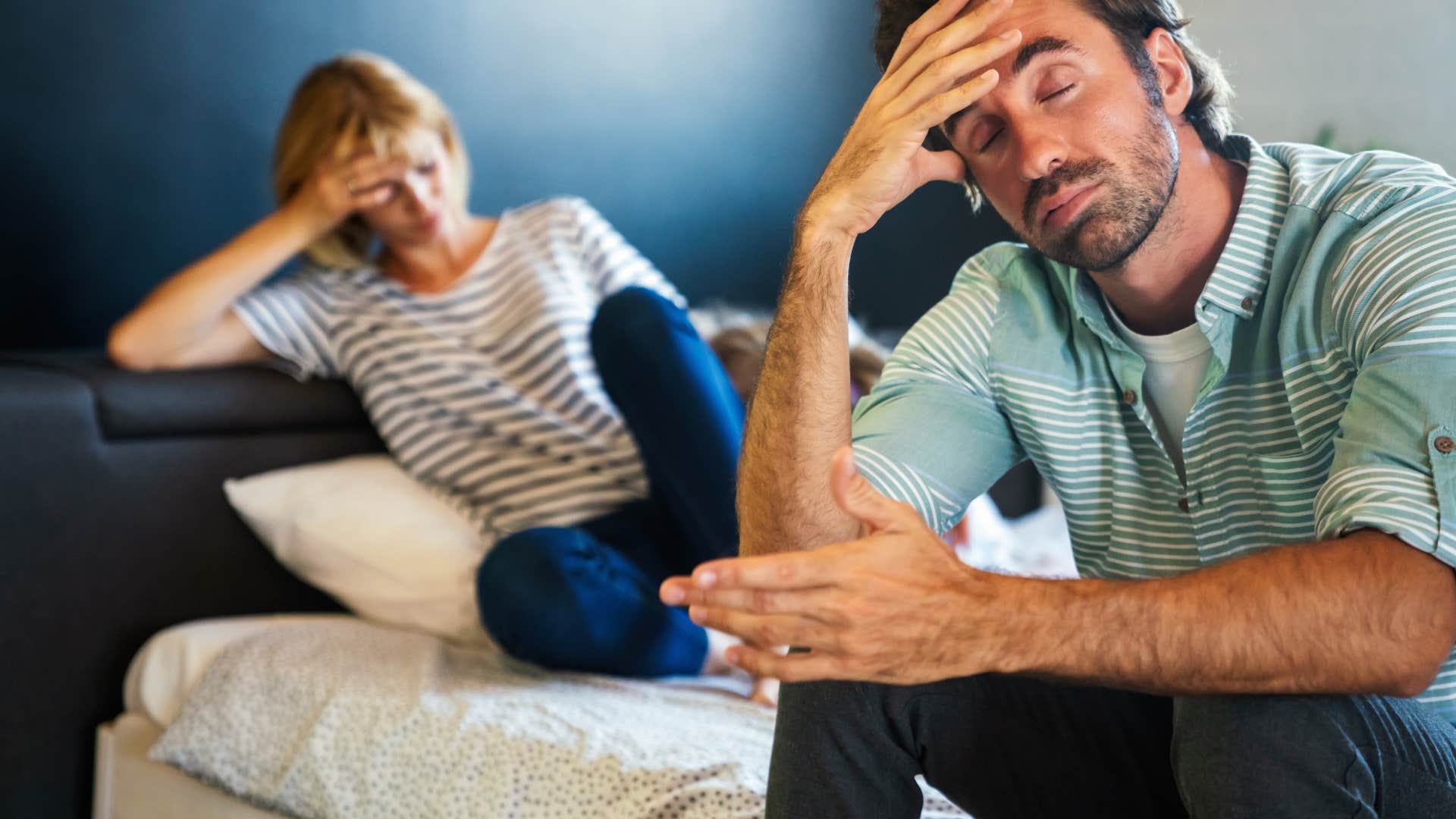 stressed couple sitting on opposite ends of the bed