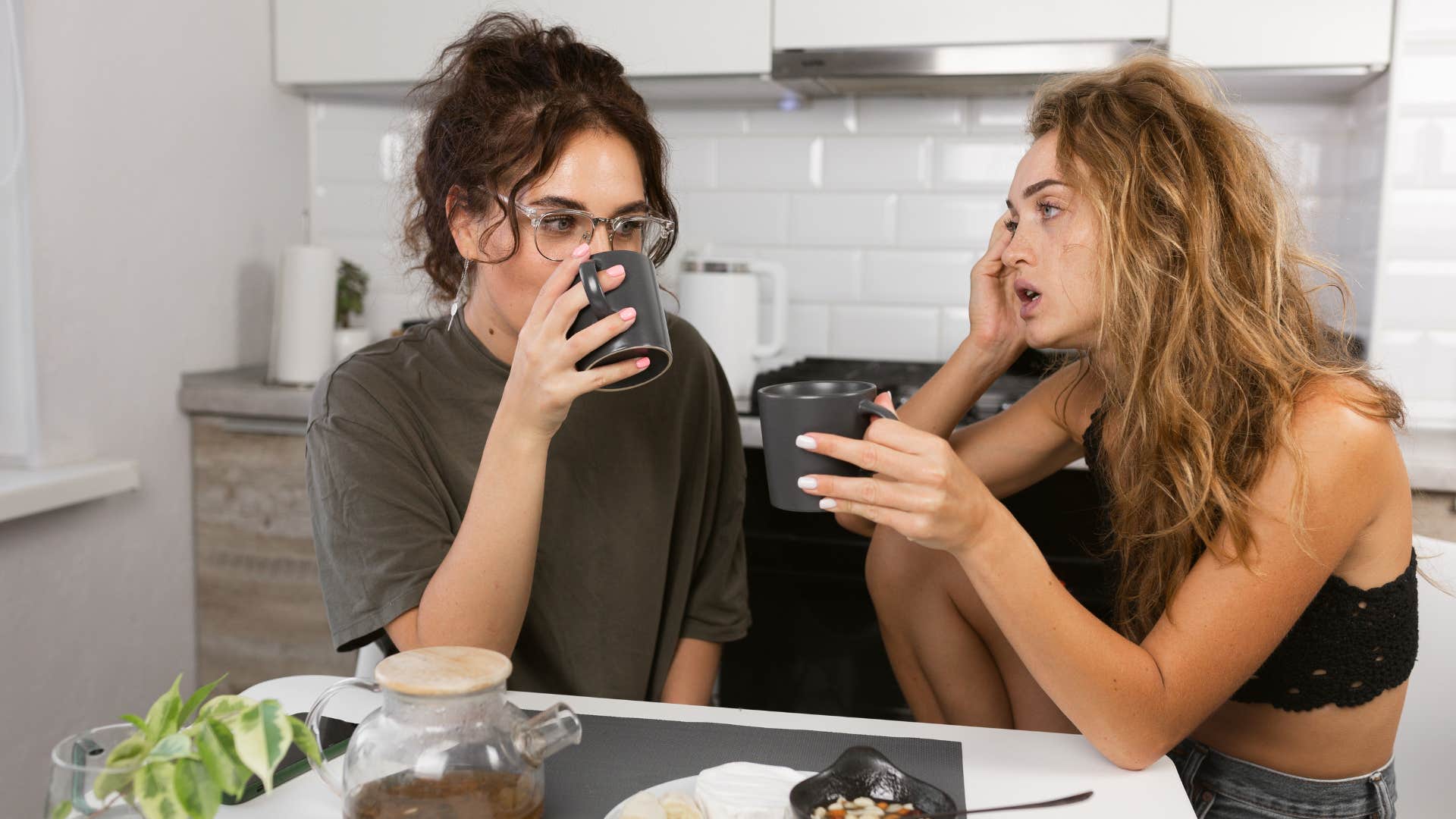 two women drinking coffee together in tense situation
