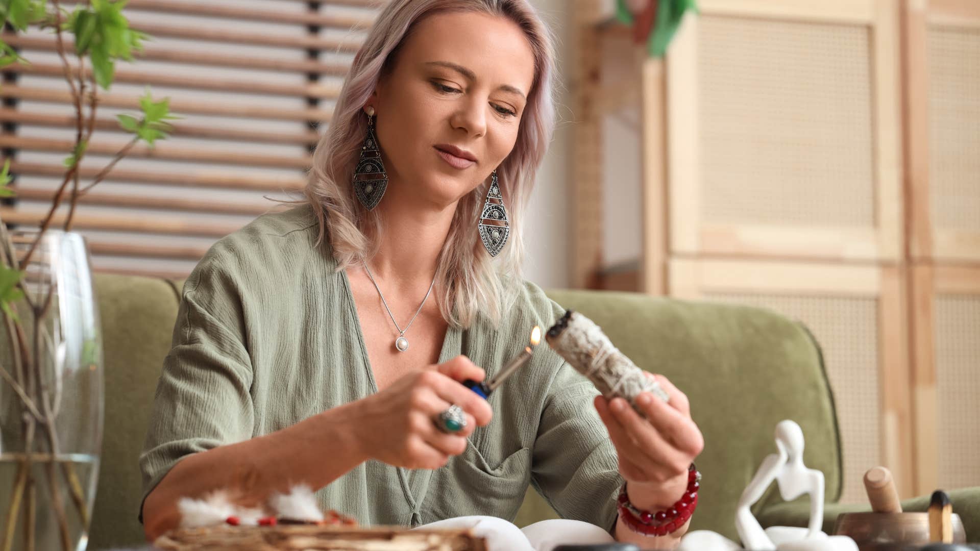 woman doing manifestation ritual of burning bay leaves with sage