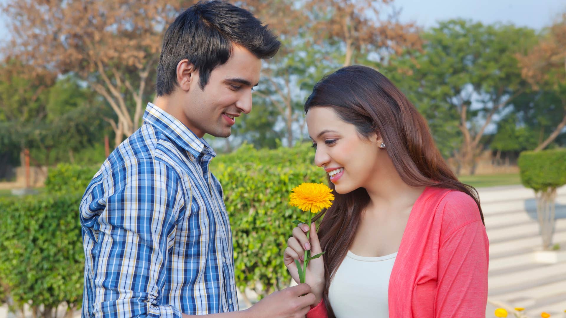 man giving woman flower as he understands how important small gestures are