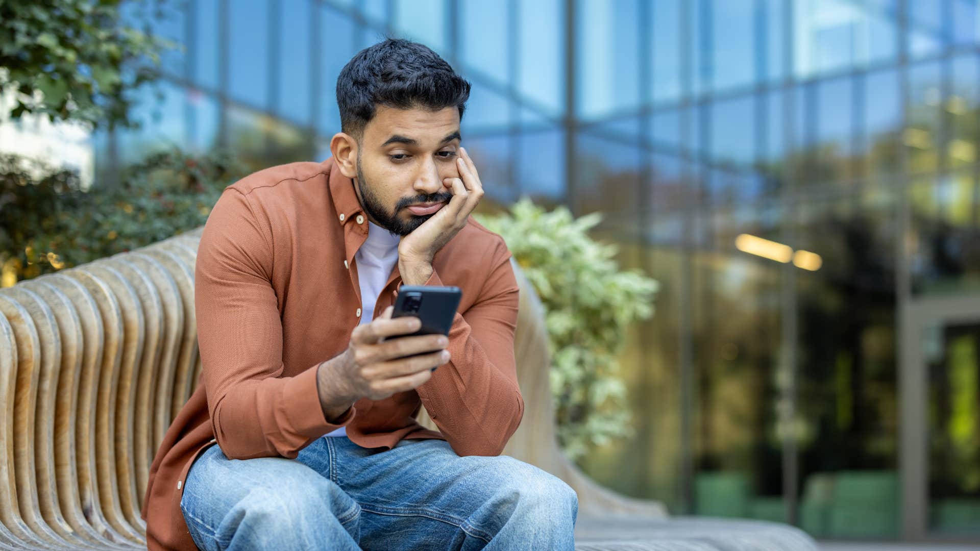 man in brown jacket becomes inconsistent as he's on phone looking bored