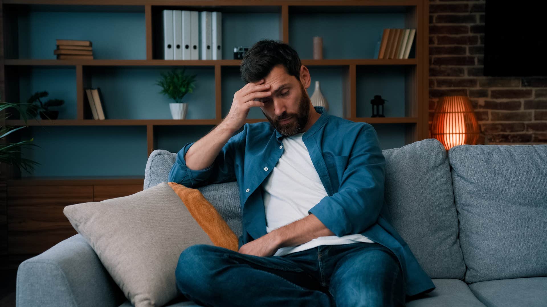 man sitting on couch feeling anxious