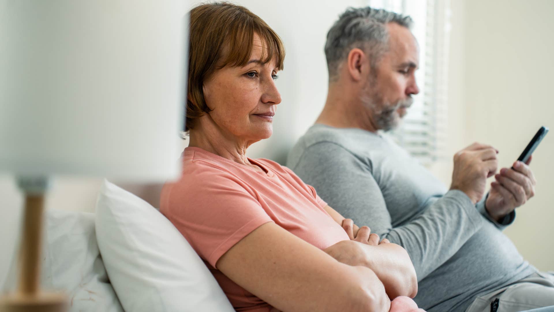 man on his phone refusing to give his upset wife a compliment